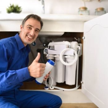 Technician installing reverse osmosis equipment under the sink with ok sign. Front view. Horizontal composition.